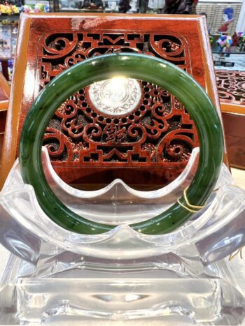 A green jade bangle sitting on top of a clear glass table.