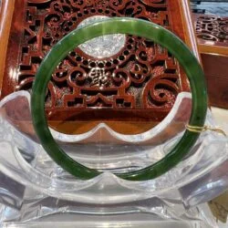 A green jade bangle sitting on top of a wooden table.