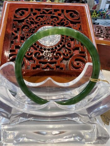 A green jade bangle sitting on top of a wooden table.