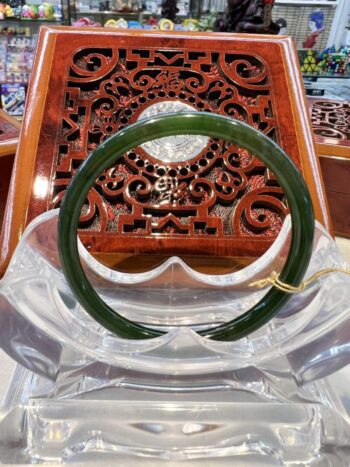 A green jade bangle sitting on top of a glass table.