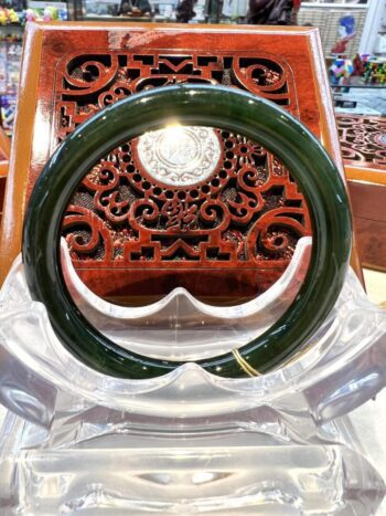 A green bangle sitting on top of a wooden chair.