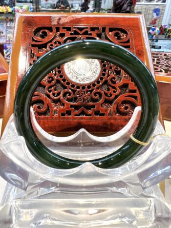 A green bangle sitting on top of a wooden chair.