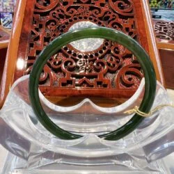 A green jade bangle sitting on top of a glass table.