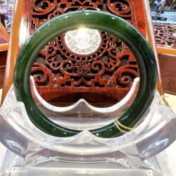 A green bangle sitting on top of a clear plastic stand.