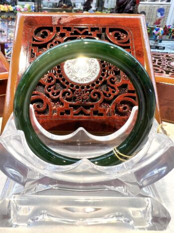 A green bangle sitting on top of a clear plastic stand.