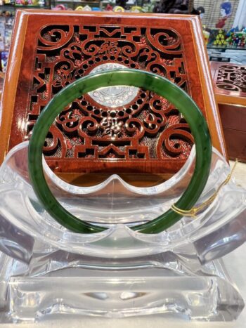 A green jade bangle sitting on top of a clear plastic bowl.