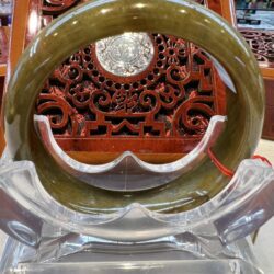 A large green bangle sitting on top of a clear plastic stand.