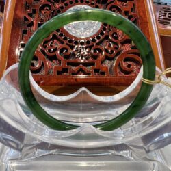 A green bangle sitting on top of a wooden table.