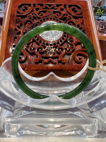 A green bangle sitting on top of a wooden table.