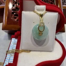 A white purse with a green stone on it