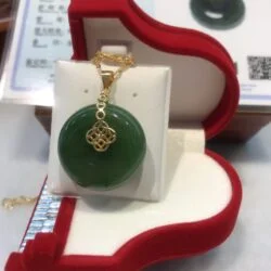 A green jade pendant sitting in a red box.