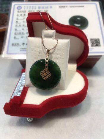 A green jade pendant sitting in a red box.