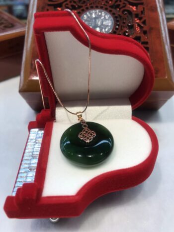 A green glass pendant sitting in a red box.