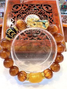 A round glass plate with an orange bead bracelet.