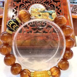 A round glass plate with an orange bead bracelet.