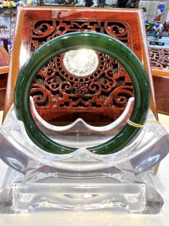 A green bangle sitting on top of a clear glass bowl.