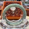 A green jade bangle sitting on top of a clear glass bowl.