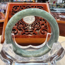 A green jade bangle sitting on top of a clear glass bowl.