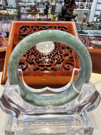 A green jade bangle sitting on top of a clear glass bowl.