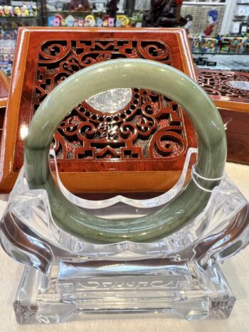 A large green jade bangle sitting on top of a clear glass bowl.