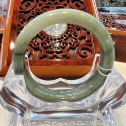 A large green jade bangle sitting on top of a clear glass bowl.