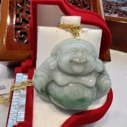 A green buddha statue sitting in a red box.