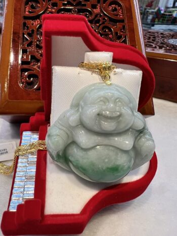 A green buddha statue sitting in a red box.