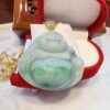 A green jade buddha pendant sitting on top of a red box.