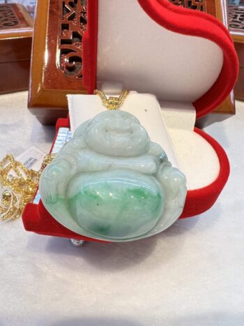 A green jade buddha pendant sitting on top of a red box.