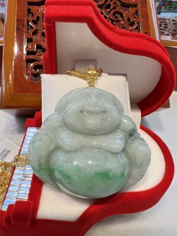 A green jade buddha sitting on top of a red box.