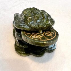 A turtle statue sitting on top of a coin.