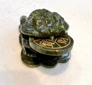 A turtle statue sitting on top of a coin.