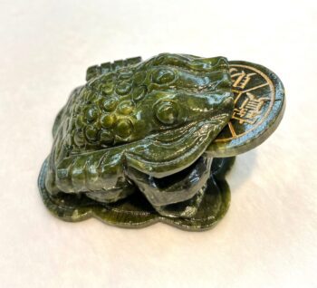 A green frog sitting on top of a coin.