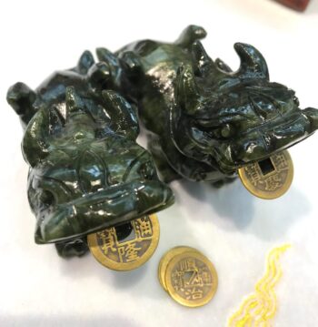 A pair of green frog statues with gold coins.