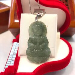 A green jade pendant sitting on top of a red box.