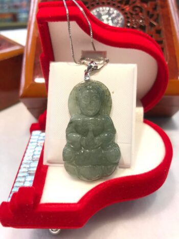 A green jade pendant sitting on top of a red box.