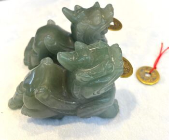 A green stone statue of two animals with gold coins.