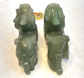 A pair of green glass elephants sitting on top of the ground.