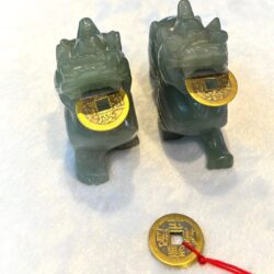 A pair of green chinese dragon statues with gold coins.