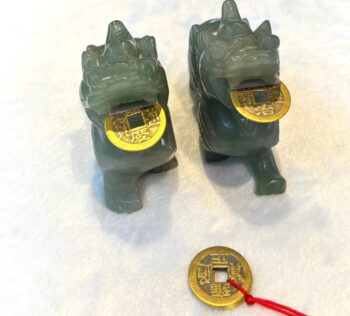 A pair of green chinese dragon statues with gold coins.