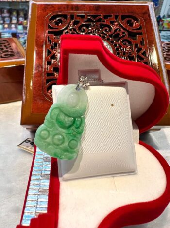 A green glass ornament sitting on top of a red box.