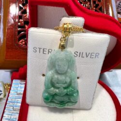 A green jade buddha is sitting on top of a white box.