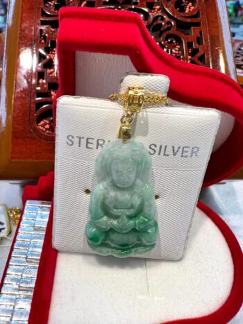 A green jade buddha is sitting on top of a white box.