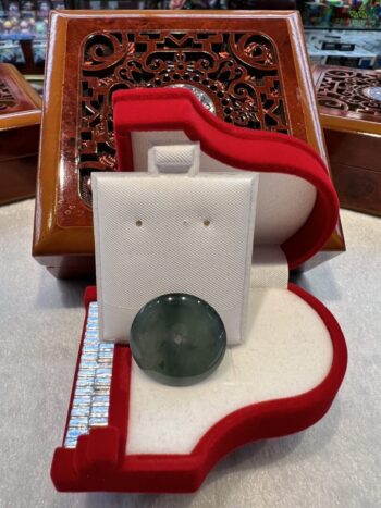 A white earring holder with a green glass bead in it.