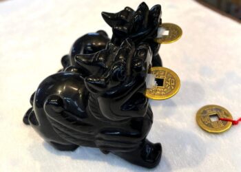 A black statue of an elephant with gold coins.