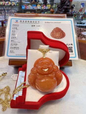 A gold chain with an orange buddha pendant.