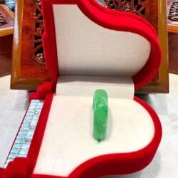 A green glass bead in the middle of a red box.