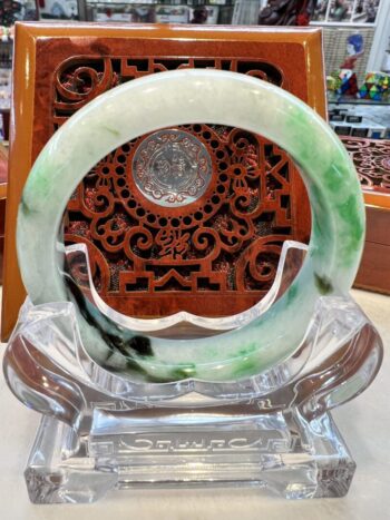 A green and white bracelet sitting on top of a glass plate.