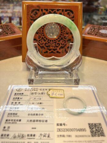 A display of an asian jade bangle on a table.