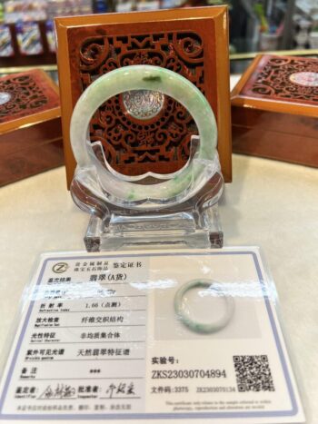 A green jade bracelet sitting on top of a table.